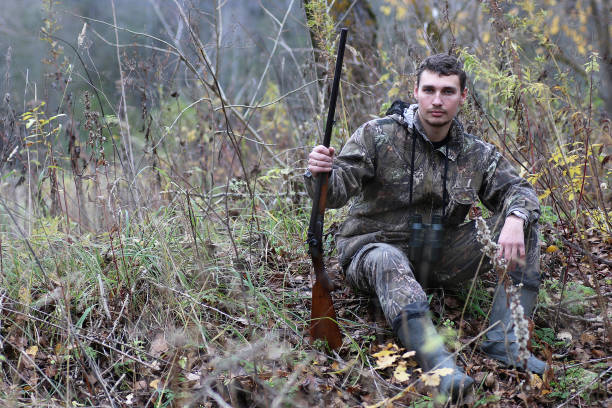 istock Man in camouflage and with guns in a forest belt on a spring hun 664178444