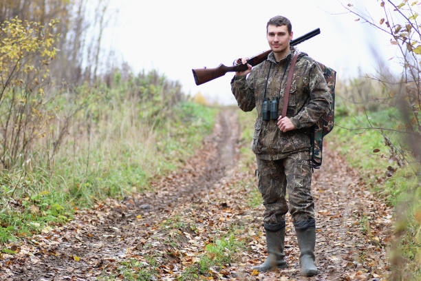 istock Man in camouflage and with guns in a forest belt on a spring hun 664178496