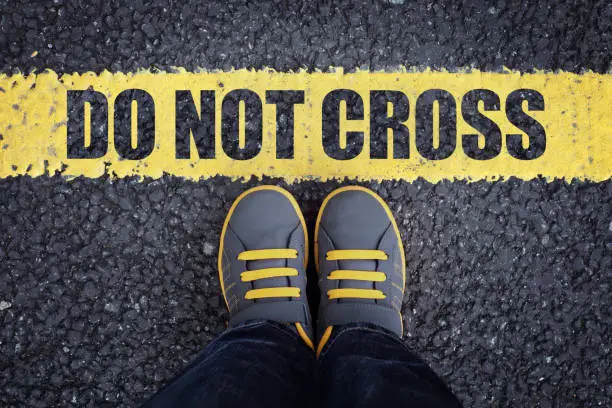 Do not cross line child in sneakers standing next to a yellow line with restriction or safety warning
