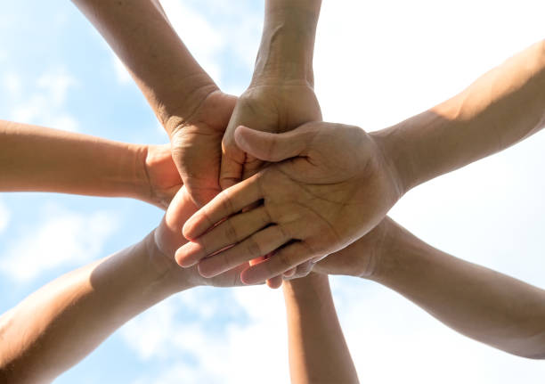 istock Hands of people team close up on blue sky background 664202536