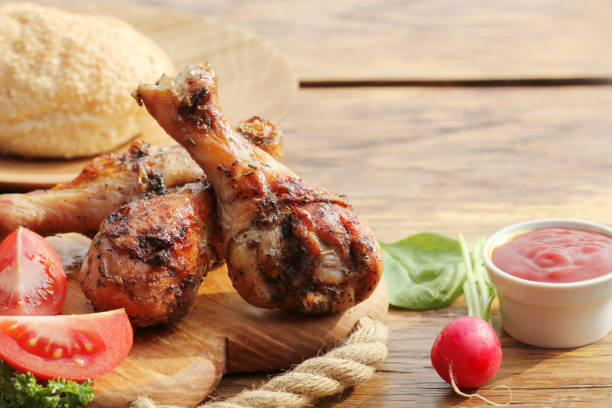 istock Grilled chicken legs on wooden background.Rustic dinner table. 664207024