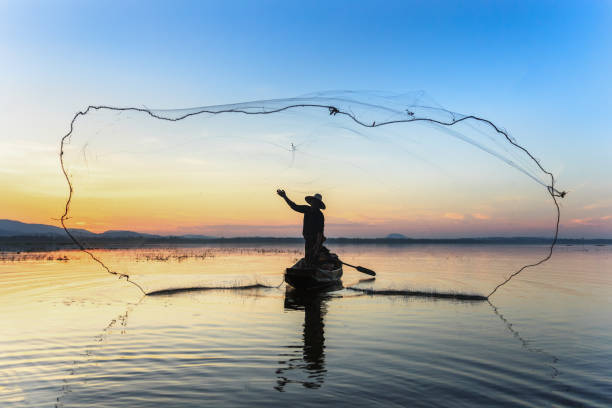silhouette рыбак на рыбацкой лодке настройки сети с восходом солнца - burmese culture myanmar old outdoors стоковые фото и изображения