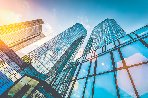 Bottom view of modern skyscrapers in business district in beautiful evening light at sunset with monochrome retro vintage Instagram style filter and lens flare effect