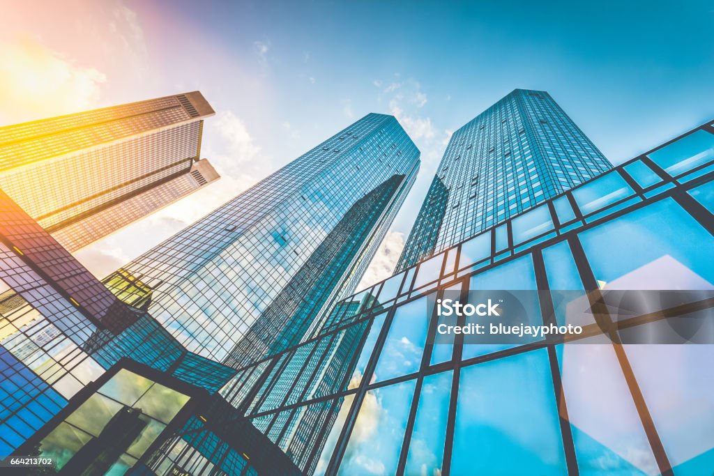 Modern skyscrapers in business district at sunset with lens flare effect Bottom view of modern skyscrapers in business district in beautiful evening light at sunset with monochrome retro vintage Instagram style filter and lens flare effect Construction Industry Stock Photo