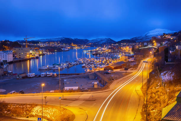 A lot of small boats are parking in the harbor of Kristiansund. in the background the mountain Freikollen is visible. the street on the right side is leading to the city center.