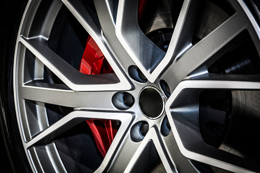 Close-up of modern alloy car wheel. The brake disc is visible behind of wheel bars.