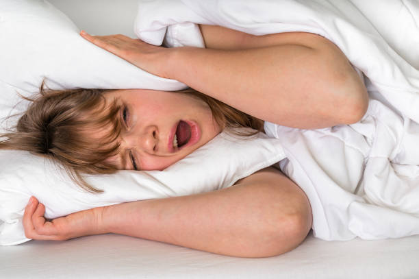 istock Woman with head under her pillow trying to sleep 664225222