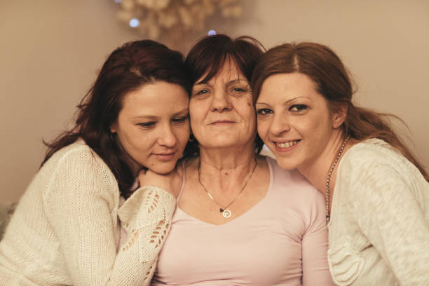 istock two adult daughters sitting on sofa and hugging their mother 664232604