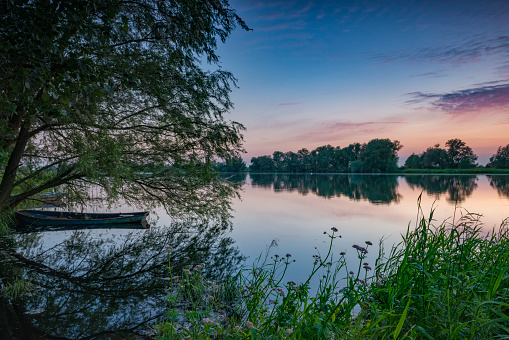 Colorful sunset over a lake next to the river IJssel in Overijssel, The Netherlands during a calm sunset at the end of a beautiful spring day.