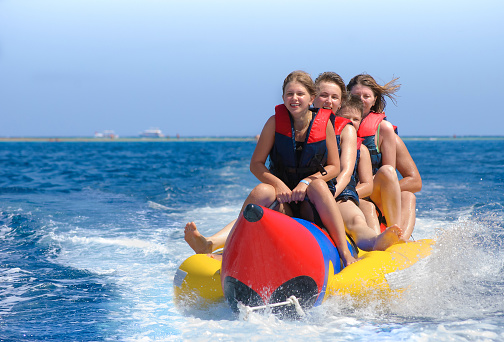 People ride on banana boat. Bright blue sea and clear sky. Happy vacation.