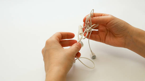 Woman untangling tangled earbuds or earphone knot with hands