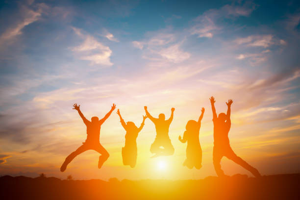 Silhouette of happy business team making high hands in sunset sky background for business teamwork concept. stock photo