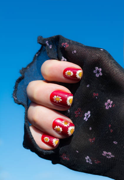 Sun shaped dendilions on red nails in the summer