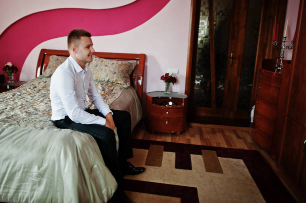 istock Groom sitting on bed at his room on morning wedding. 664254246