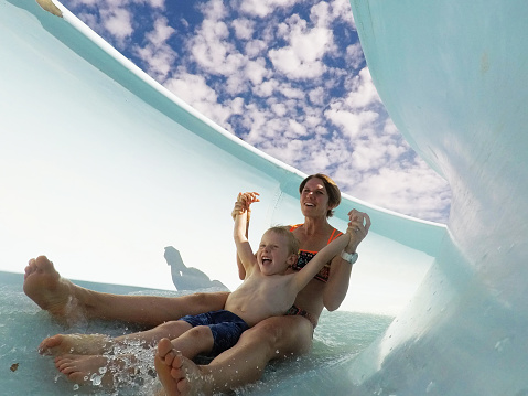 Mother and son have a great time sliding down the water slide