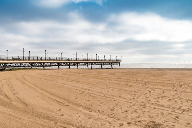 View along the pier in Skegness in Lincolnshire, UK. Wind turbines in the background.