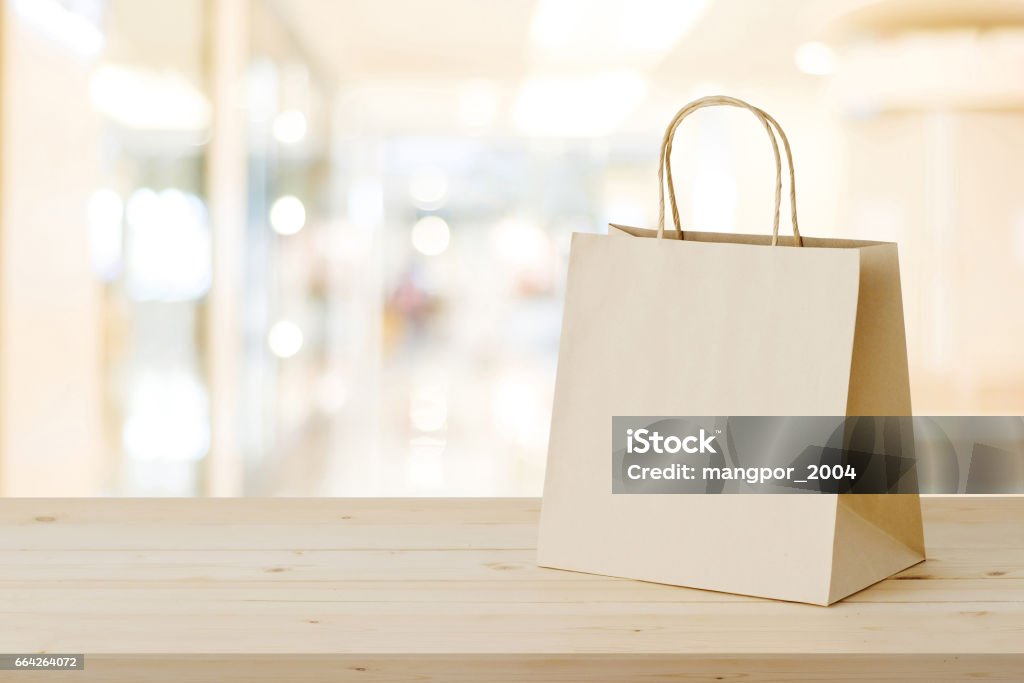 Brown paper shopping bag on wood table over blurred store background, business, template, retail, sale Bag Stock Photo