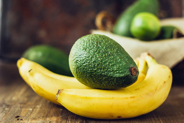 Avocado and banana over brown wooden background. Avocado and banana over brown wooden background avocado brown stock pictures, royalty-free photos & images