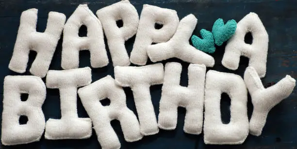 Happy birthday background from knitted alphabets from yarn, handmade white letter for special day