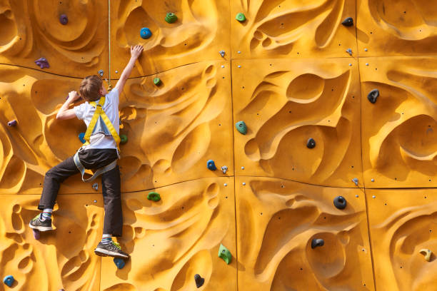 Child climbing a rock wall outdoor - bouldering