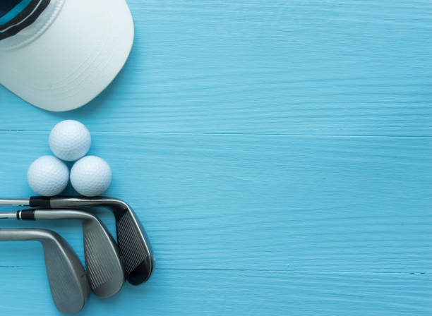 Golf clubs, golf balls, cap, on blue wooden table