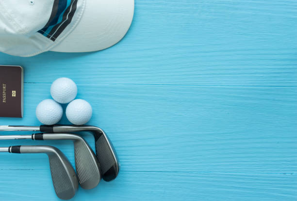 Golf clubs, golf balls, cap, passport on blue wooden table stock photo