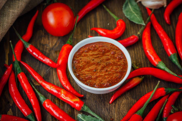 istock Red hot chili peppers and salsa or adjika in white ceramic bowl. 664304608