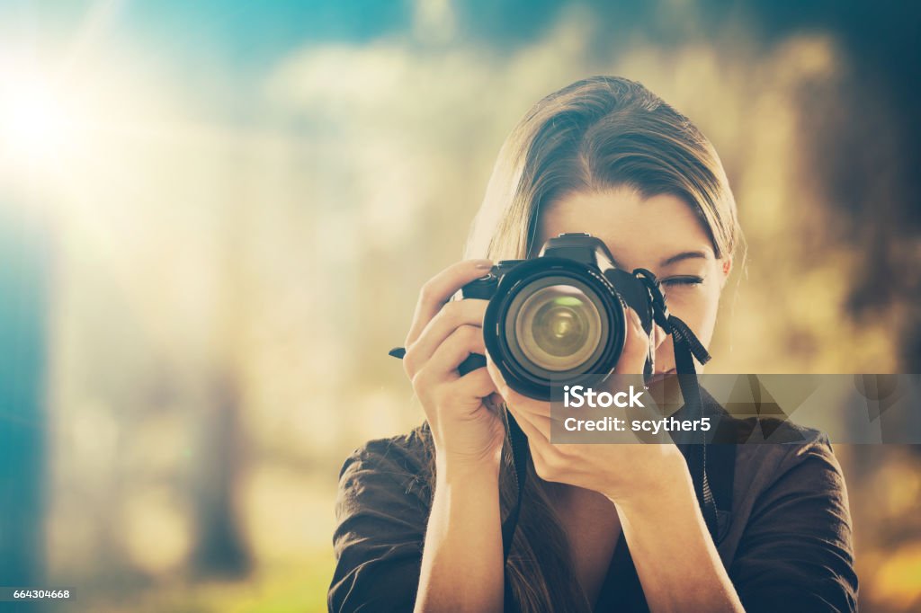 Portrait of a photographer covering her face with camera. photographer camera dslr photo person portrait photographing girl joy make photography taking concept - stock image Photographer Stock Photo
