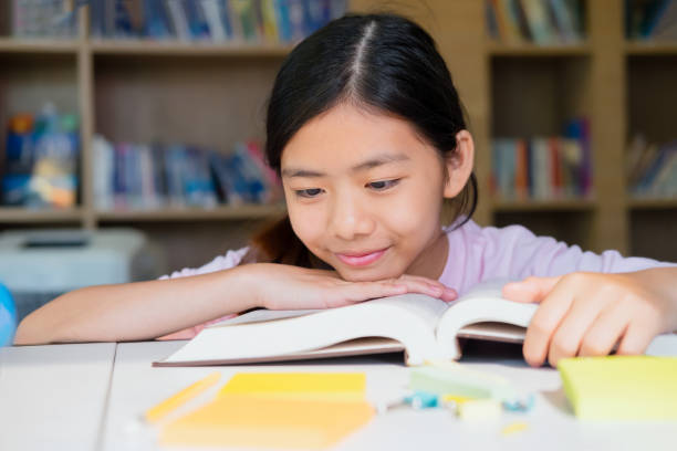 istock School girl reading book in library. 664307562