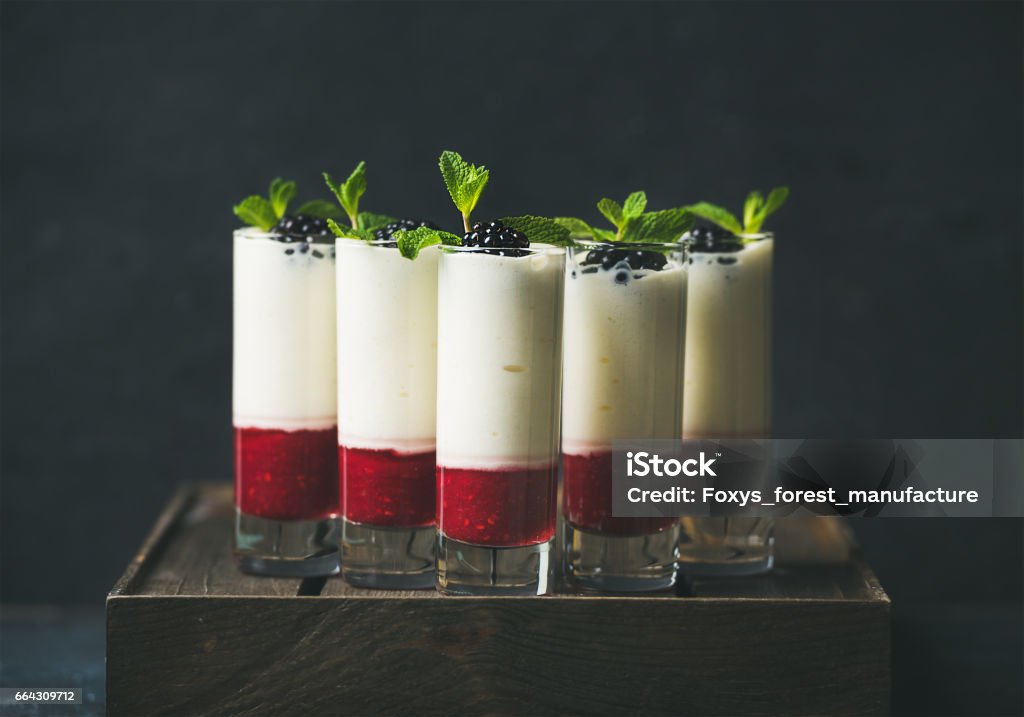 Dessert in glass with blackberries and mint over dark background Catering, banquet or party food concept. Dessert in glass with blackberries and mint leaves over dark background on corporate event, christmas, birthday, wedding celebration, selective focus Food Service Occupation Stock Photo
