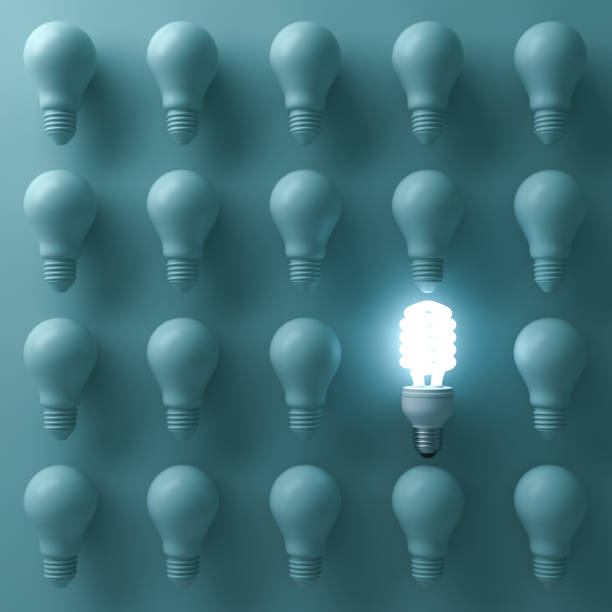 istock Energy saving light bulb , one glowing compact fluorescent lightbulb standing out from unlit incandescent bulbs on green background , individuality and different creative idea concepts . 3D render 664317408