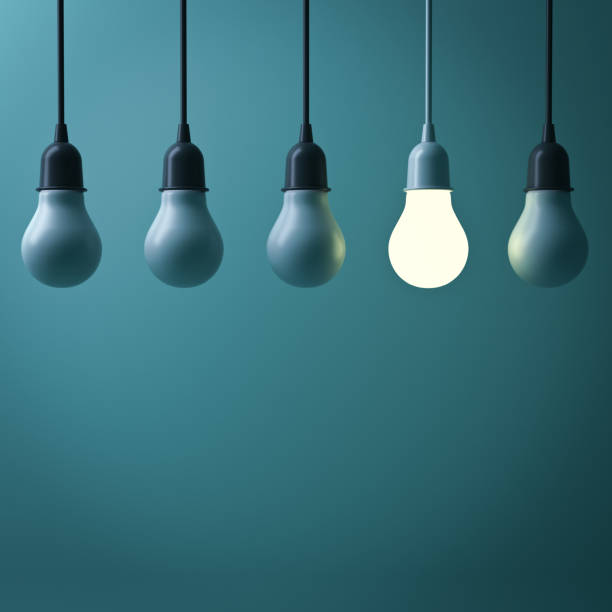 istock One hanging light bulb glowing different standing out from unlit incandescent bulbs with reflection on dark green background , leadership and different business creative idea concept. 3D render 664317670