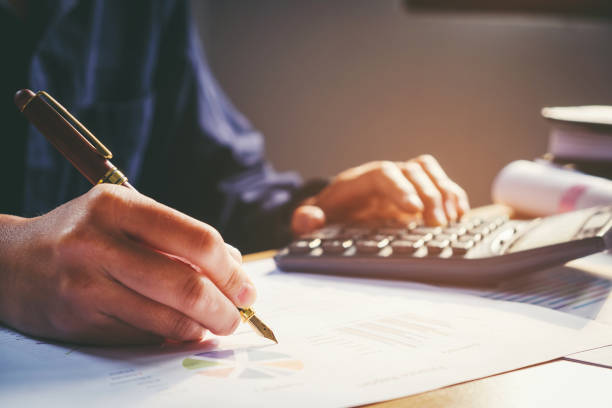istock Businessman's hands with calculator at the office and Financial data analyzing counting on wood desk 664321986