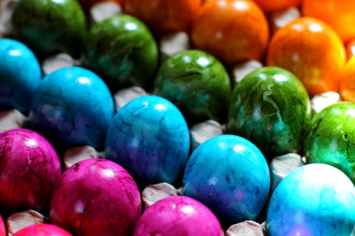 Dyed handmade Easter eggs in a row on green colored background