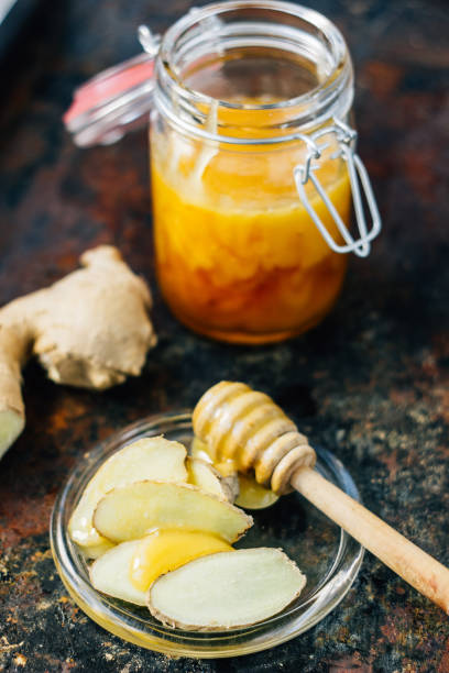 istock Honey spoon with bit of honey and ginger root on glass plate. 664328324