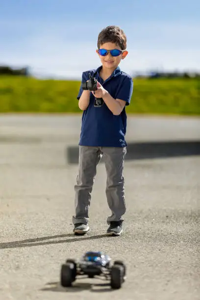 Young boy with a RC car playing outside on a bright sunny day.