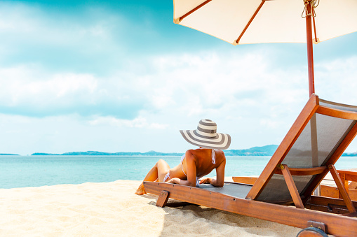 Woman in sunhat sunbathing in beach chair