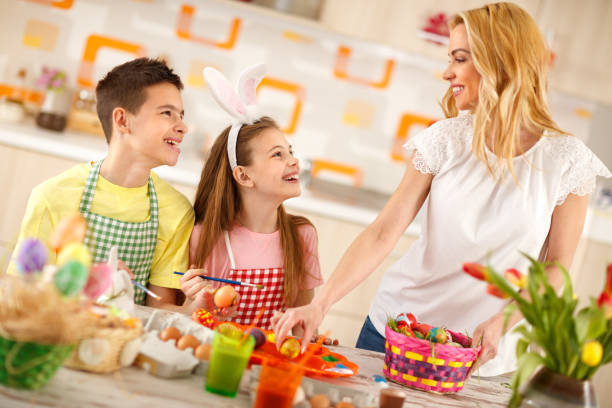 istock Mother and children preparing Easter basket with eggs 664348632