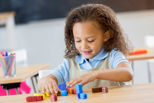 istock Adorable little girl counts with blocks in classroom 664349158