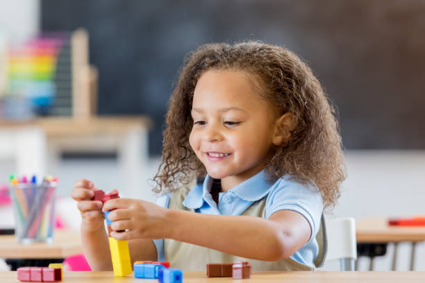 веселая девочка детского сада играет с блоками в классе - block stack stacking cube стоковые фото и изображения