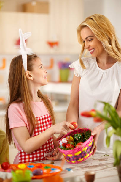 istock Girl with mother preparing Easter basket with eggs 664351336