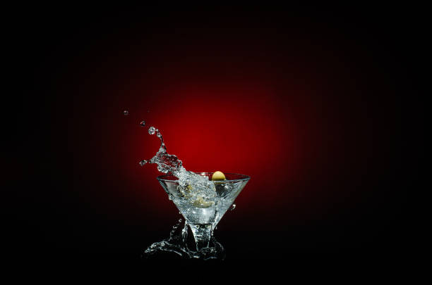 istock Olive splashing on cocktail isolated on red and black background 664364796