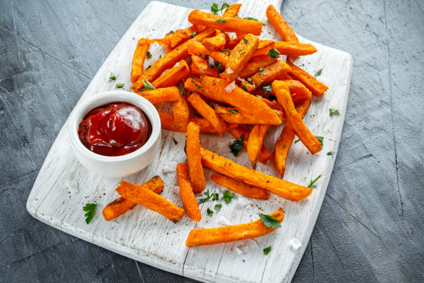 Healthy Homemade Baked Orange Sweet Potato Fries with ketchup, salt, pepper on white wooden board Healthy Homemade Baked Orange Sweet Potato Fries with ketchup, salt, pepper on white wooden board. sweet potato french fries stock pictures, royalty-free photos & images