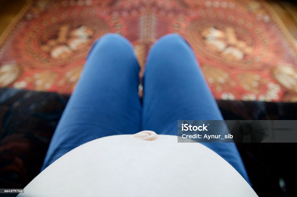 Pregnant belly. selfie view from above. Prenatal period, pregnancy health, prepared for child birth concept Pregnant belly of sitting woman relaxing on sofa. selfie view from above. Expecting baby birth in third trimester for being mother. Prenatal period, pregnancy health, prepared for child birth concept Adult Stock Photo