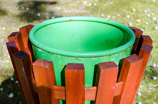 Green bin at a park, surrounded by a wooden structure.