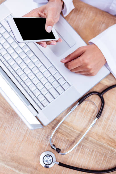 istock Doctor using smartphone on wooden desk 664399124