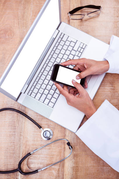 istock Doctor using smartphone on wooden desk 664403462