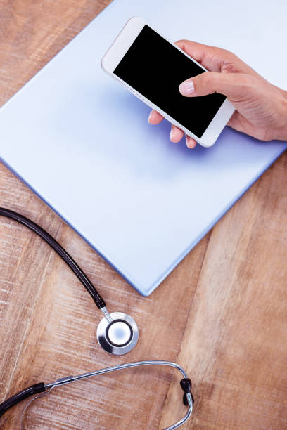 istock Doctor using smartphone on wooden desk 664406424
