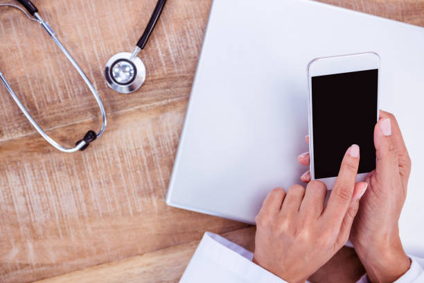 istock Doctor using smartphone on wooden desk 664406548