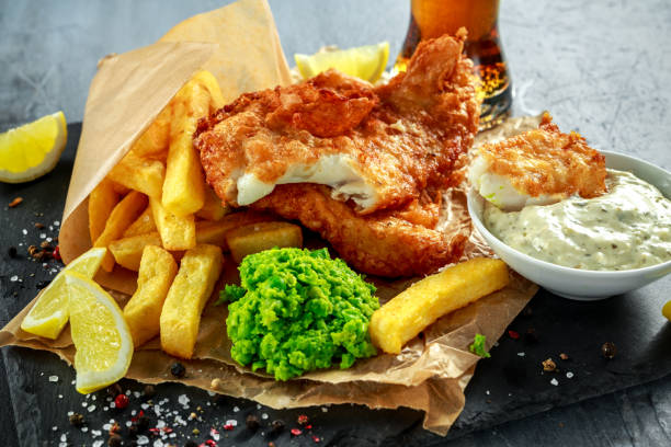 istock British Traditional Fish and chips with mashed peas, tartar sauce on crumpled paper with cold beer. 664406744